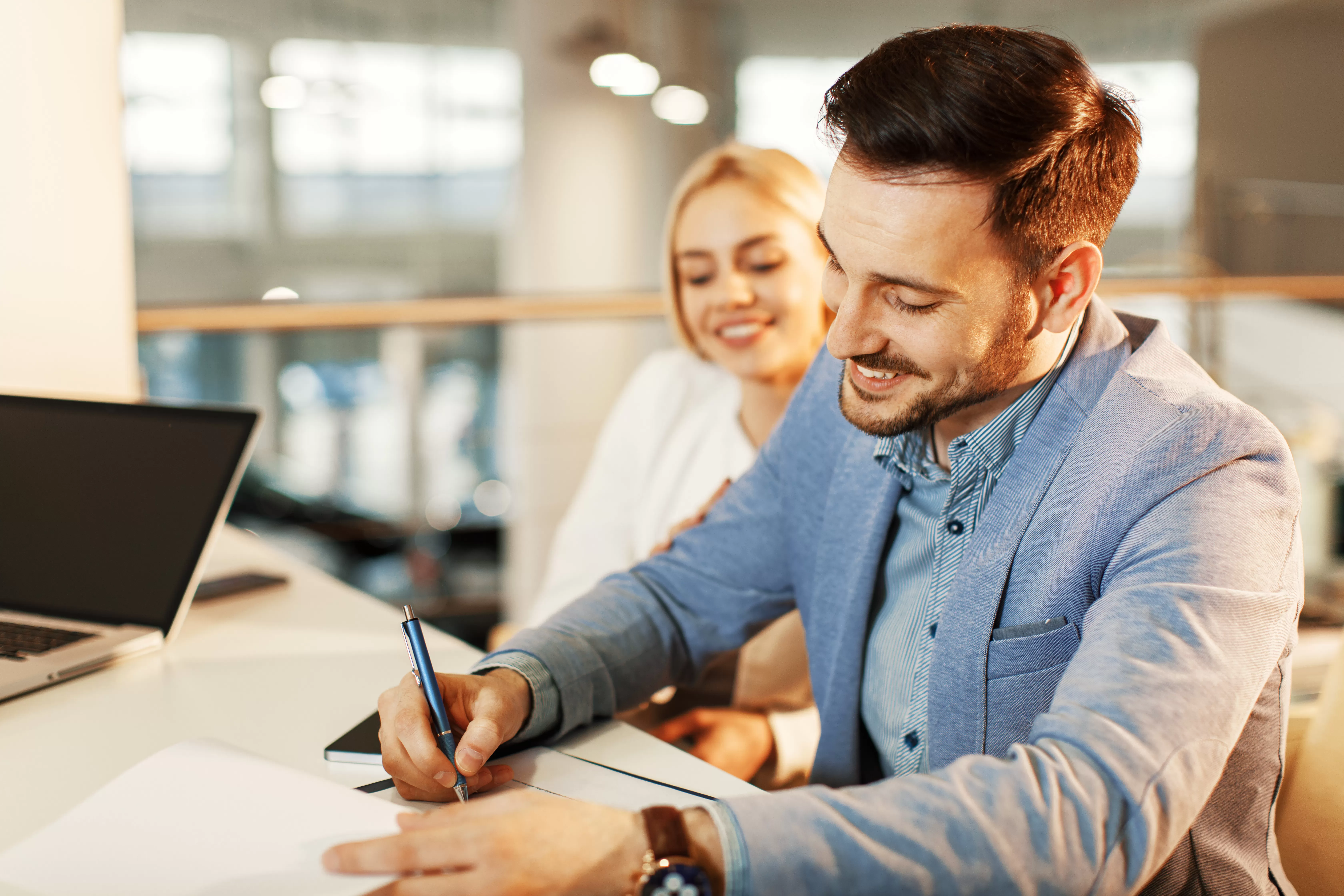 Smiling couple signing document to pay off auto loan early