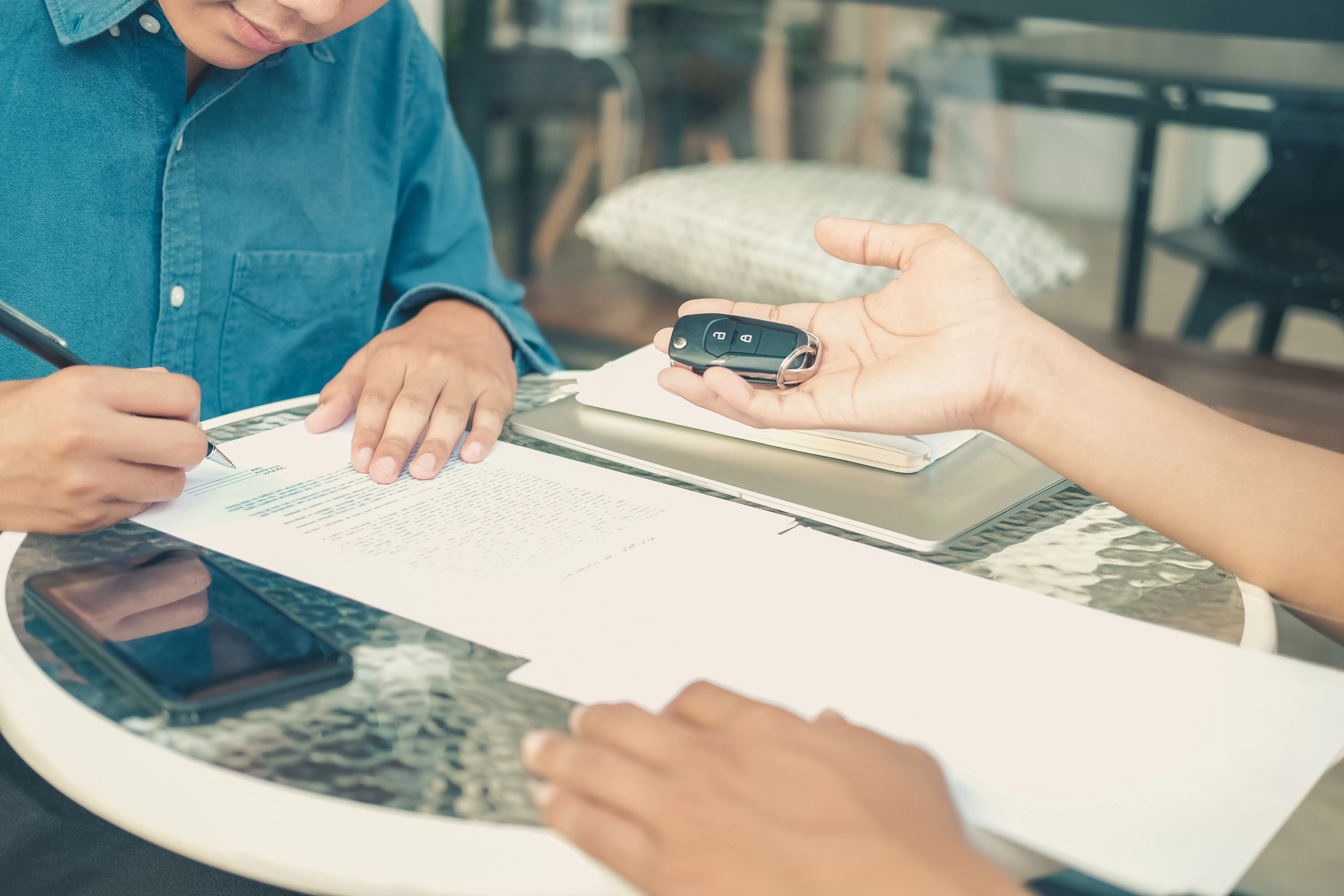 a man reviews finance charges on his car loan with his lender before being handed the keys to his new vehicle