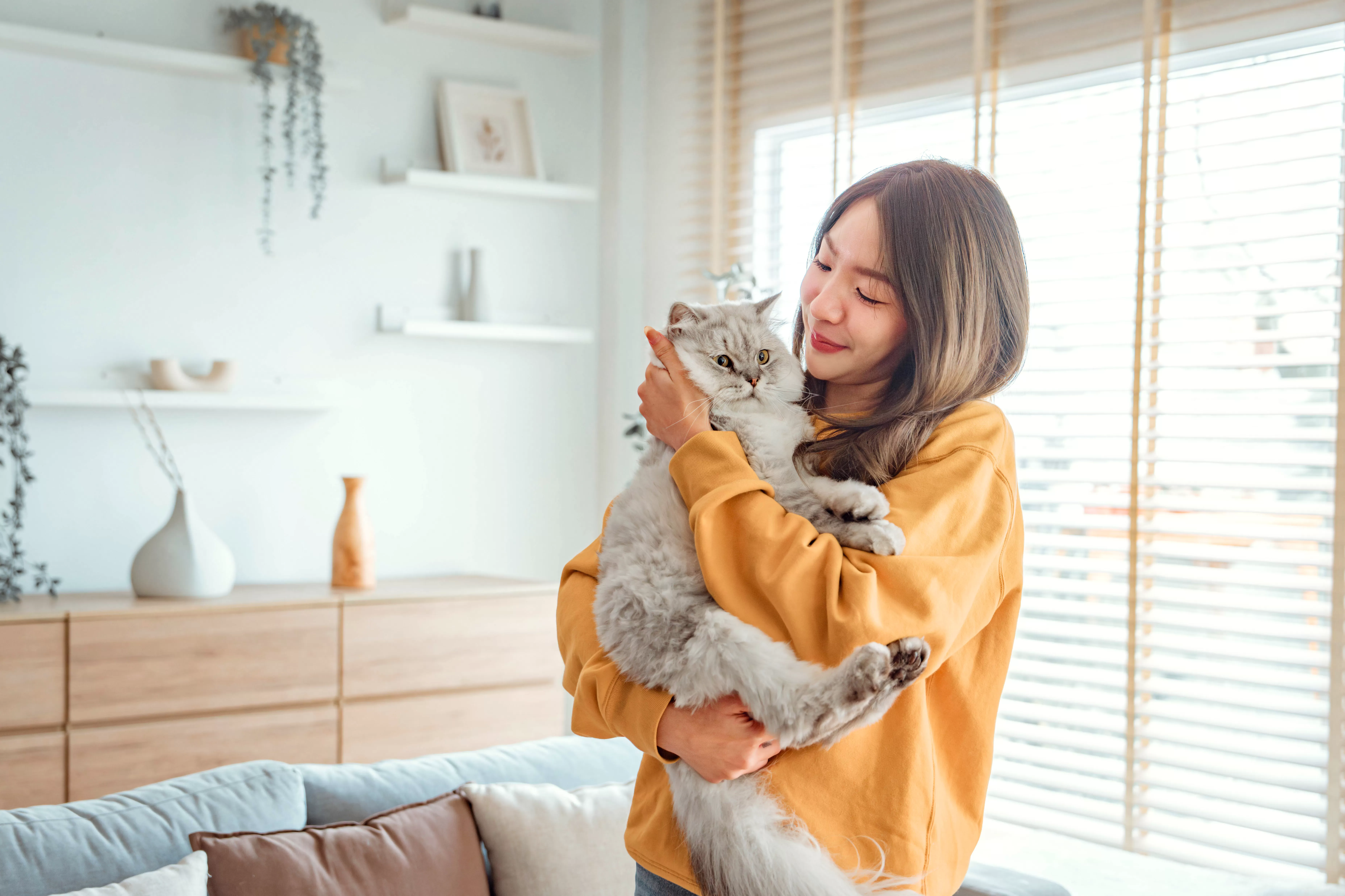 Woman holding her cat in her living room